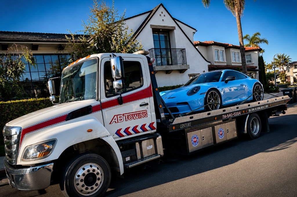 A&B Towing white flatbed tow truck transporting a luxury vehicle
